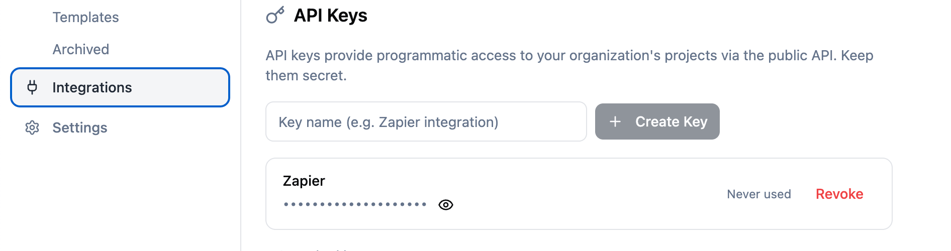 The Integrations page with an API Keys panel: a name field with a Create Key button, and a key named "Zapier" showing a masked value, a reveal icon, a "Never used" label, and a Revoke action